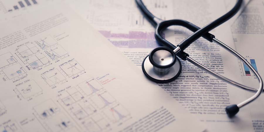 医学部進学や学費をイメージした画像。医療論文とグラフ資料の上に置かれた聴診器