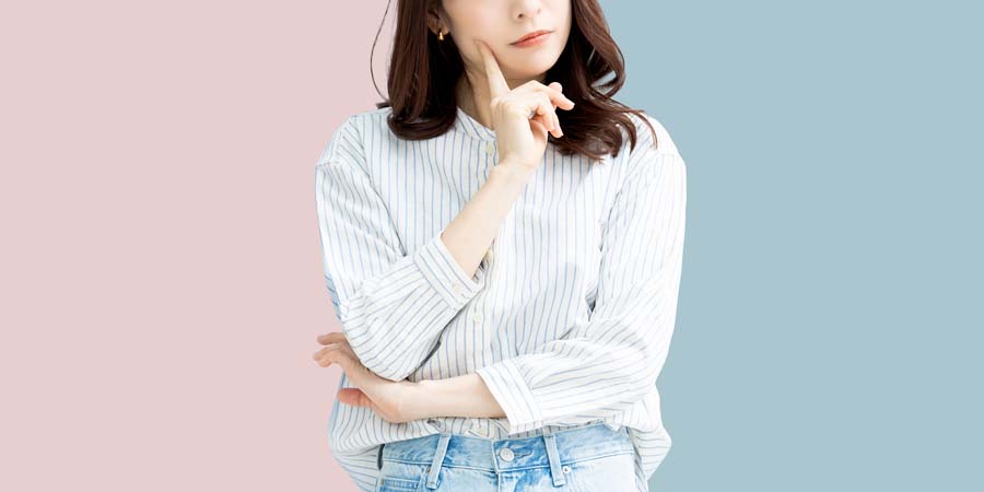 ツートンの背景を背に、考え込むような表情を見せる女性