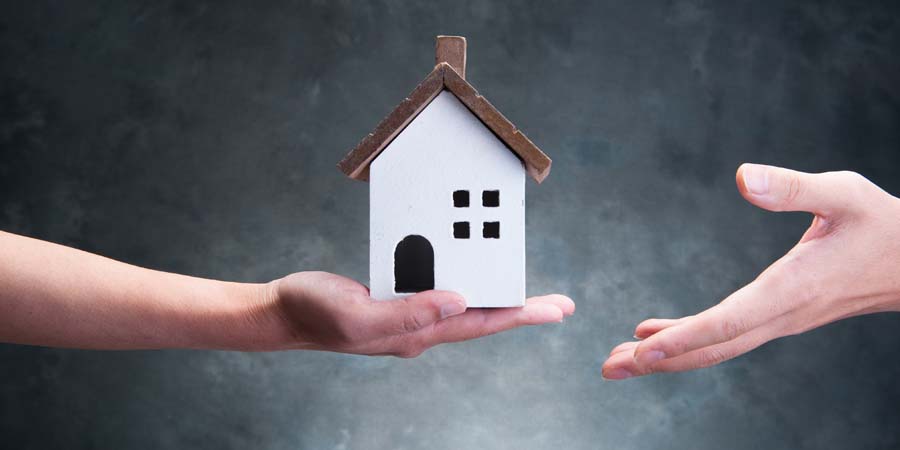 家の模型を持つ手と受け取ろうとする手。不動産のやり取りを表現したイメージ画像