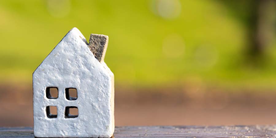 屋外に置かれた白い家の模型。明るい背景に映える不動産をイメージした画像