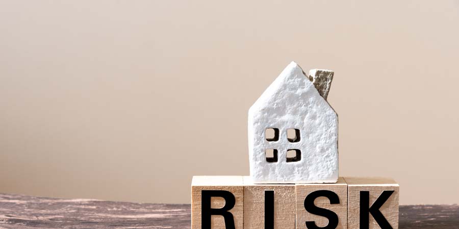 RISKと書かれたブロックの上に家の模型が置かれた写真。共有名義の不動産で不動産担保ローンを借り入れる際のリスクをイメージ