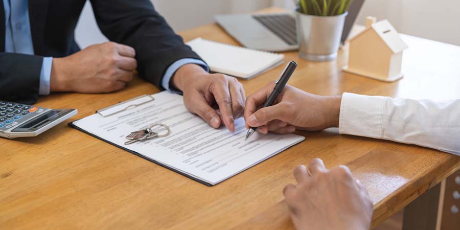 申込書類に署名する様子と金融機関担当者が確認している場面をイメージした画像