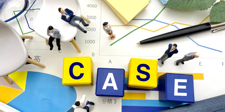 「CASE」と書かれた黄色・青色のブロックの周りに、グラフ資料・ミニチュア人形・ペン・メガネが配置されたイメージ