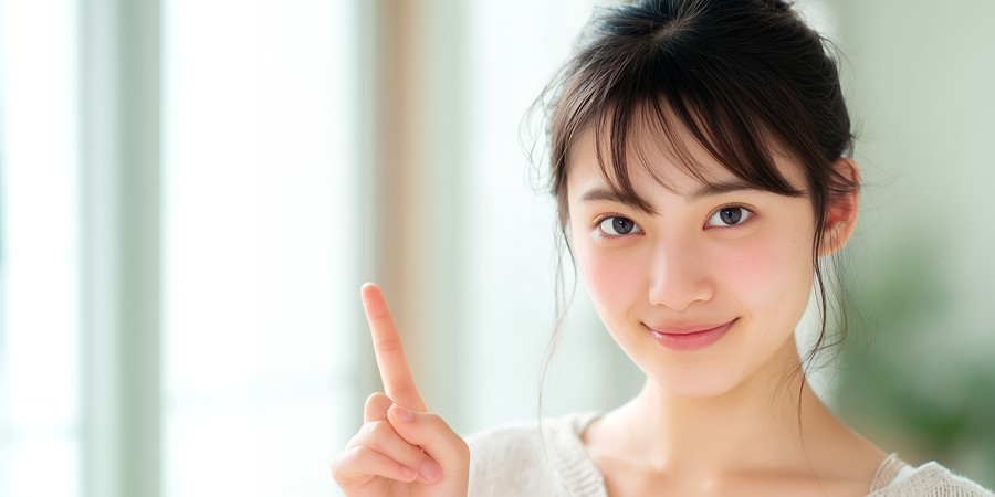 大学生のアルバイト年収の注意点をイメージした、指を立てて微笑む女性の画像