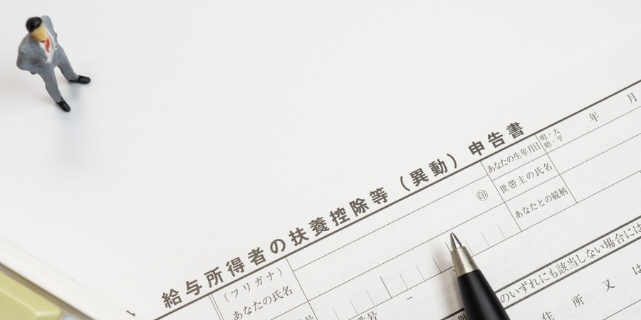 年末調整の扶養控除等申告書の書き方をイメージした、申告書の用紙とペン・電卓の画像