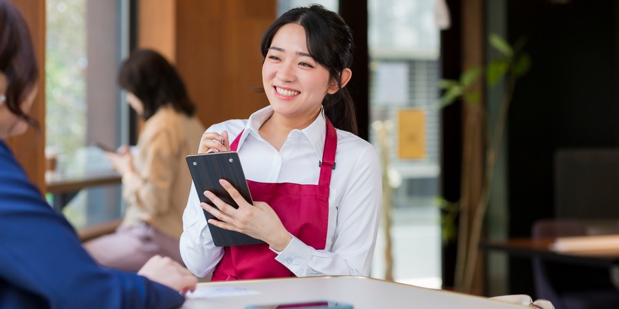 大学生のアルバイトと扶養の管理をイメージした、接客する女性店員の画像