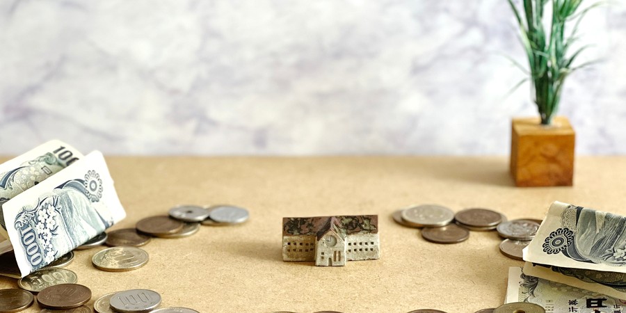 学校の建物の模型と積まれた硬貨の画像